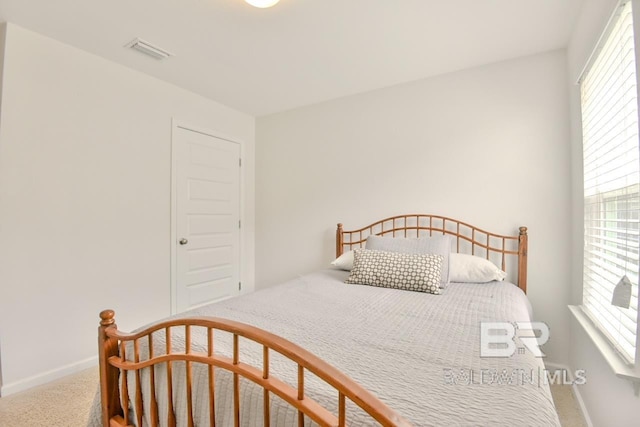 carpeted bedroom featuring baseboards, multiple windows, and visible vents