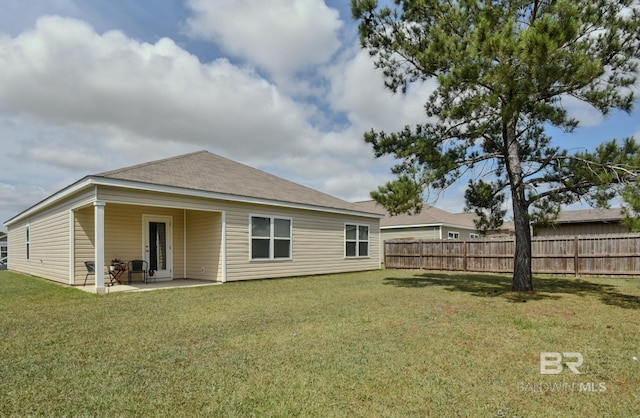 rear view of property with a yard, fence, and a patio area