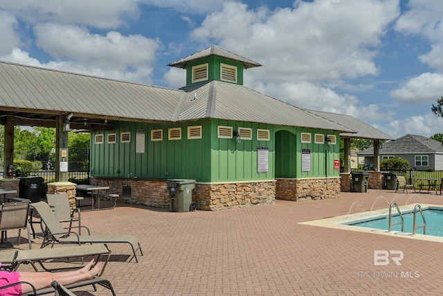 exterior space featuring board and batten siding, a patio, a community pool, and fence