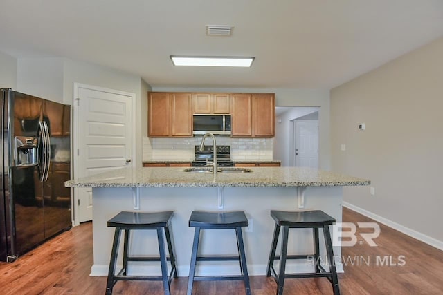 kitchen featuring a sink, dark wood finished floors, visible vents, appliances with stainless steel finishes, and decorative backsplash