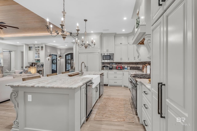 kitchen with decorative light fixtures, white cabinets, built in appliances, light stone countertops, and a spacious island