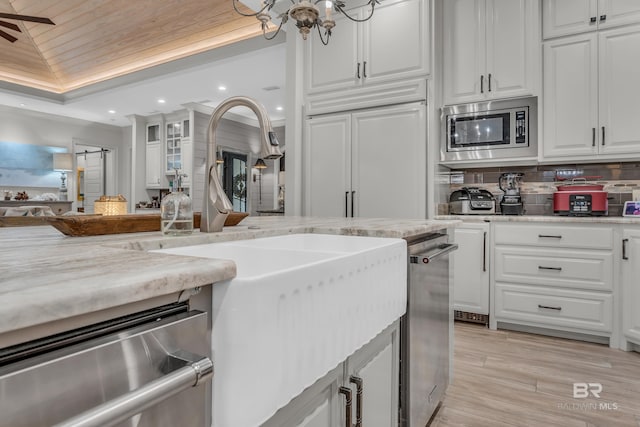 kitchen featuring tasteful backsplash, stainless steel appliances, light stone countertops, and white cabinets