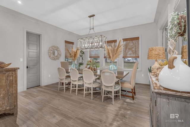 dining area featuring an inviting chandelier, ornamental molding, and light wood-type flooring