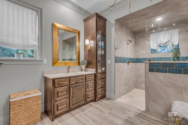 bathroom featuring tiled shower, vanity, and wood-type flooring