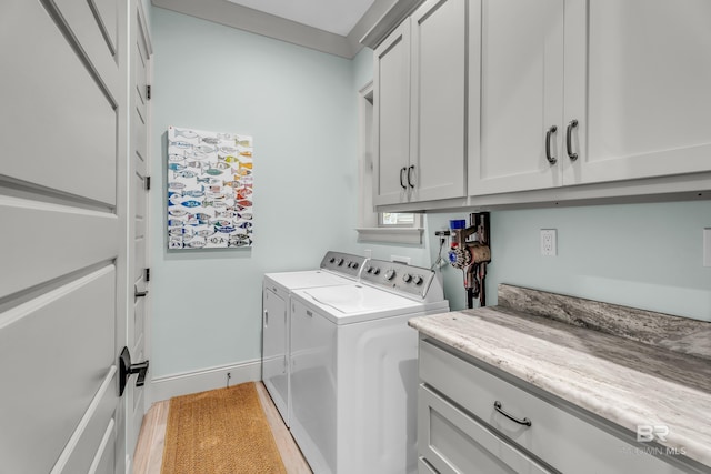 clothes washing area featuring cabinets, washer and clothes dryer, and hardwood / wood-style floors