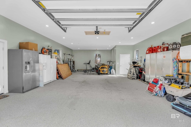 garage with a garage door opener and stainless steel fridge