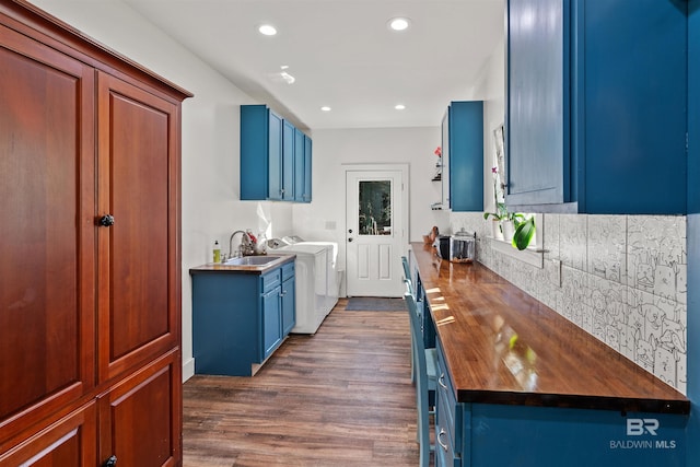 kitchen with wooden counters, sink, dark hardwood / wood-style floors, washing machine and dryer, and blue cabinetry