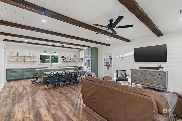 living room featuring beamed ceiling, dark hardwood / wood-style floors, ceiling fan, and wooden walls