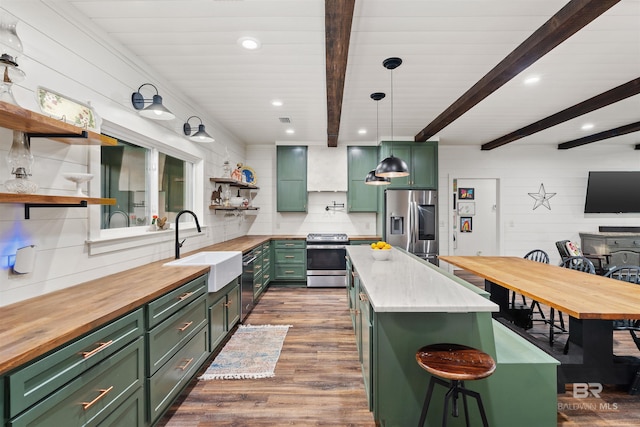 kitchen featuring beam ceiling, green cabinets, a kitchen island, and stainless steel appliances