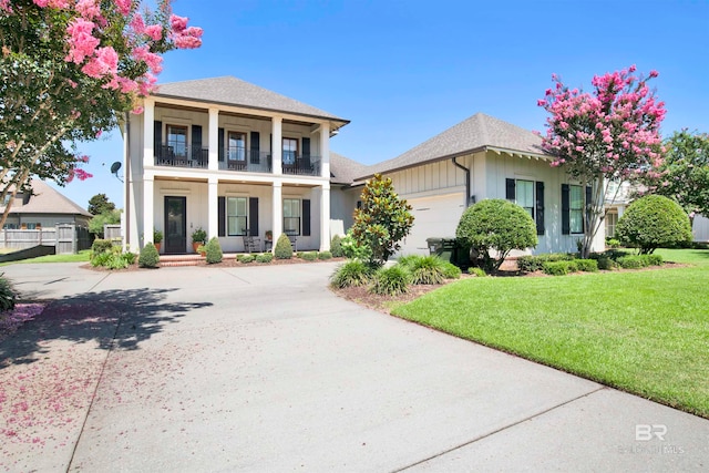 view of front of property featuring a garage, a front lawn, and a balcony