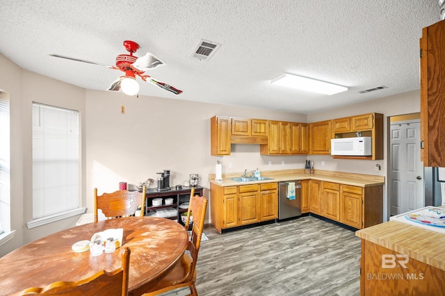 kitchen with dishwasher, sink, light hardwood / wood-style flooring, ceiling fan, and a textured ceiling