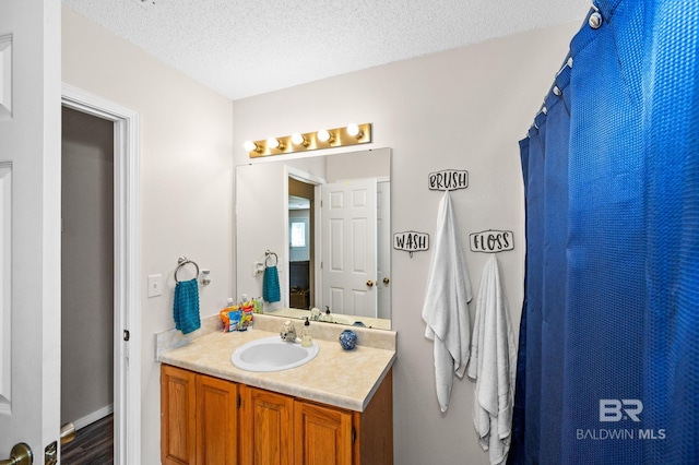 bathroom with a textured ceiling, vanity, and walk in shower