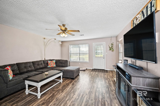 living room featuring dark hardwood / wood-style floors, ceiling fan, and a textured ceiling