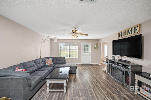 living room featuring a fireplace, dark hardwood / wood-style flooring, a textured ceiling, and ceiling fan