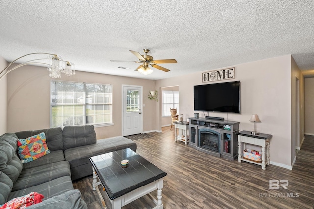 living room with ceiling fan with notable chandelier, dark hardwood / wood-style floors, and a textured ceiling