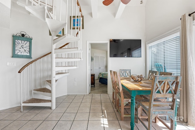 dining space with stairs, a towering ceiling, light tile patterned flooring, ceiling fan, and baseboards