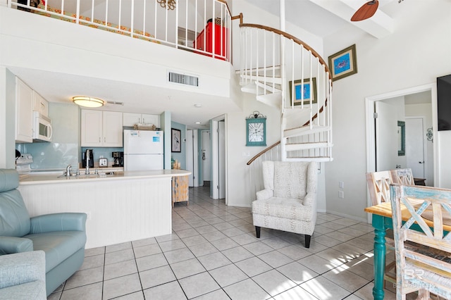 living area with stairs, a high ceiling, light tile patterned floors, and visible vents