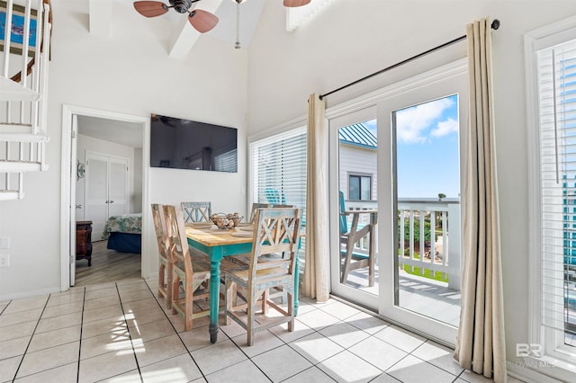 dining room featuring ceiling fan, a high ceiling, light tile patterned floors, and plenty of natural light