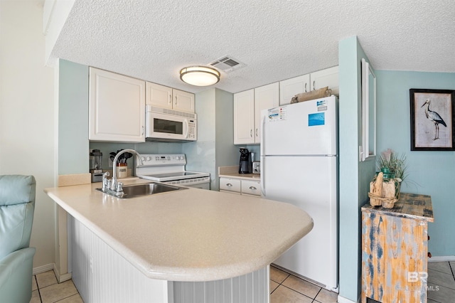 kitchen featuring a sink, a peninsula, white appliances, and light tile patterned floors