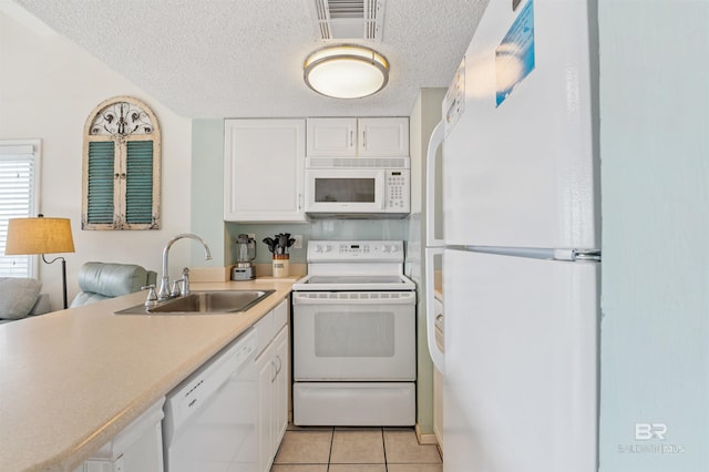 kitchen with a textured ceiling, white appliances, white cabinets, and a sink