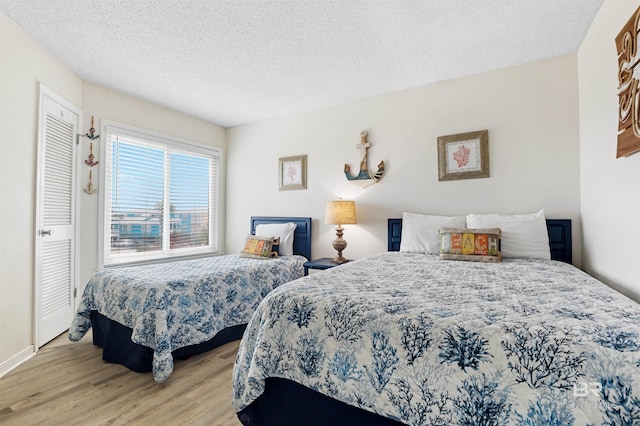 bedroom featuring a textured ceiling, baseboards, and wood finished floors