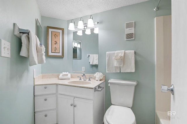 bathroom with toilet, vanity, a textured ceiling, visible vents, and a washtub