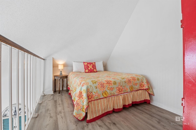 bedroom with vaulted ceiling, wood finished floors, and baseboards