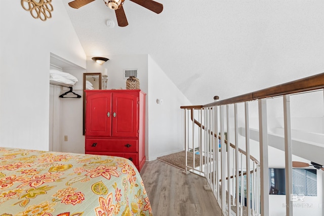 bedroom featuring ceiling fan, lofted ceiling, visible vents, and light wood-style floors
