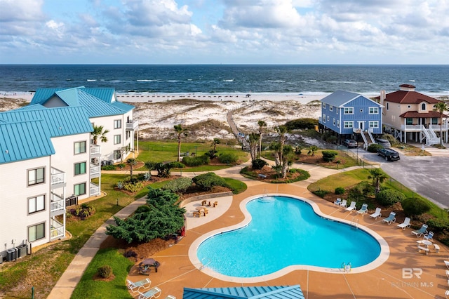 view of swimming pool featuring a view of the beach and a water view