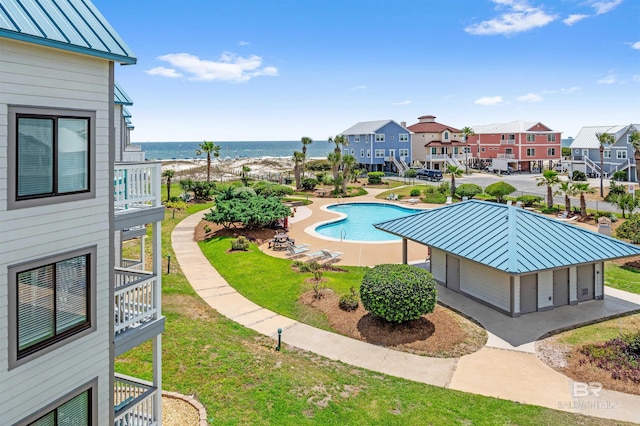 community pool featuring a yard, a water view, and a residential view