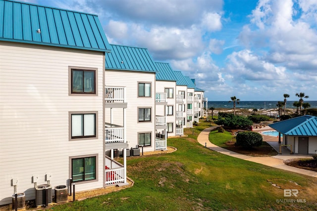 view of home's community with a water view and a lawn