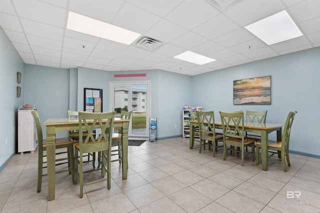 dining space with tile patterned flooring, baseboards, visible vents, and a drop ceiling