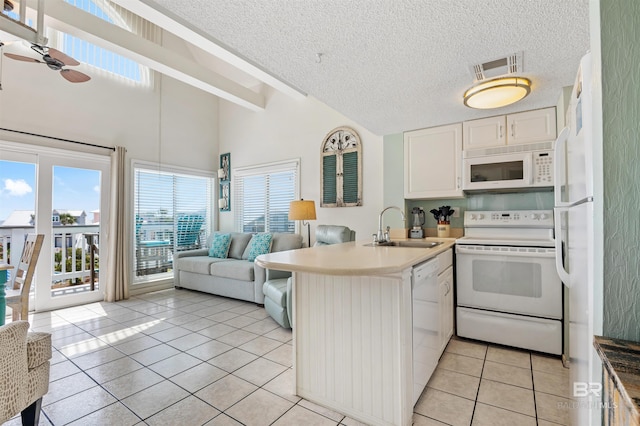 kitchen with white appliances, light tile patterned flooring, a sink, open floor plan, and a peninsula