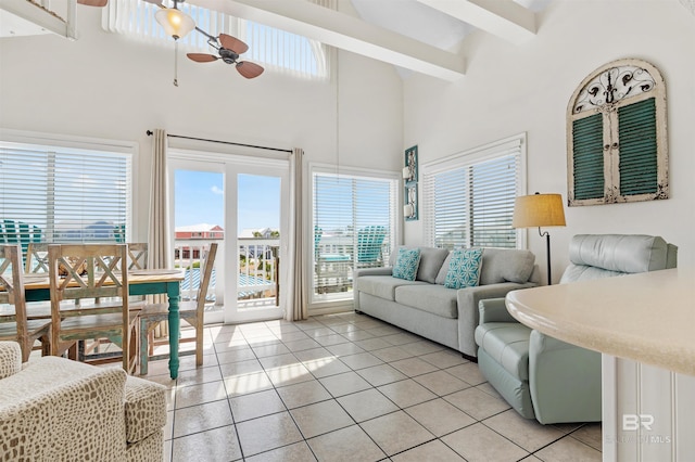 living room with a ceiling fan, a high ceiling, plenty of natural light, and light tile patterned floors