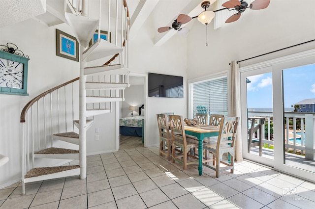 dining room with a ceiling fan, stairs, light tile patterned flooring, and a towering ceiling