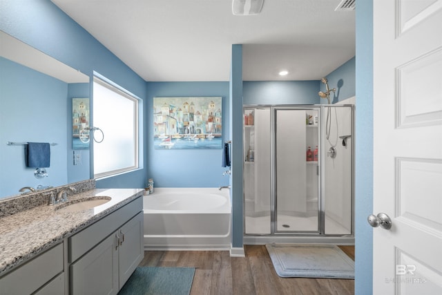 full bath with visible vents, vanity, wood finished floors, a stall shower, and a garden tub