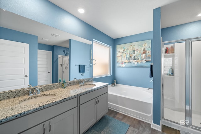 bathroom with a shower stall, a garden tub, a sink, and wood finished floors