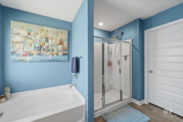 full bathroom with a bath, a stall shower, and wood finished floors