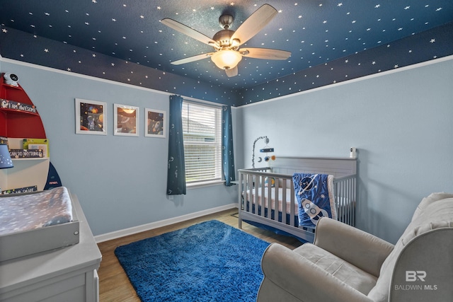 bedroom featuring a raised ceiling, wood finished floors, and baseboards