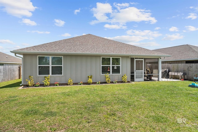 rear view of property with roof with shingles, a yard, and a fenced backyard