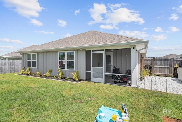 back of property with a shingled roof, a sunroom, a yard, board and batten siding, and a fenced backyard