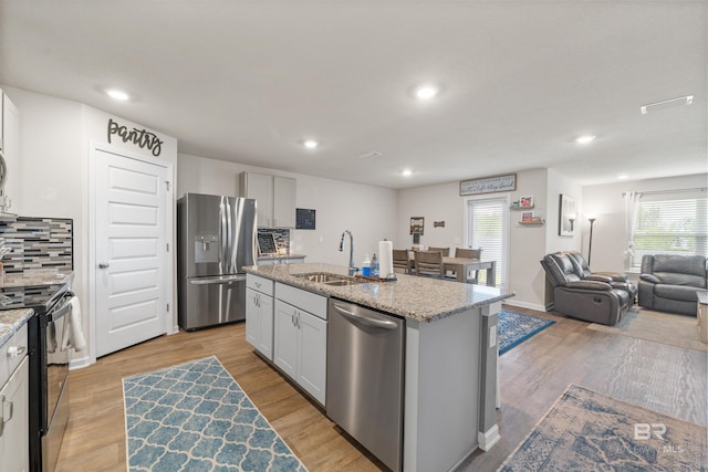 kitchen featuring a kitchen island with sink, recessed lighting, a sink, and stainless steel appliances