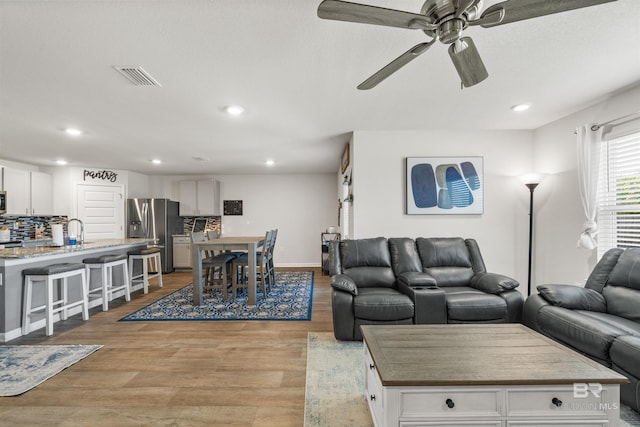 living area with visible vents, ceiling fan, recessed lighting, and light wood-style floors