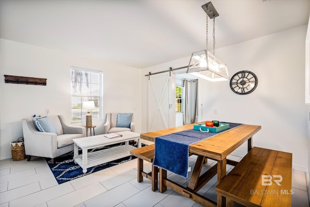 dining space featuring a barn door and light tile patterned flooring