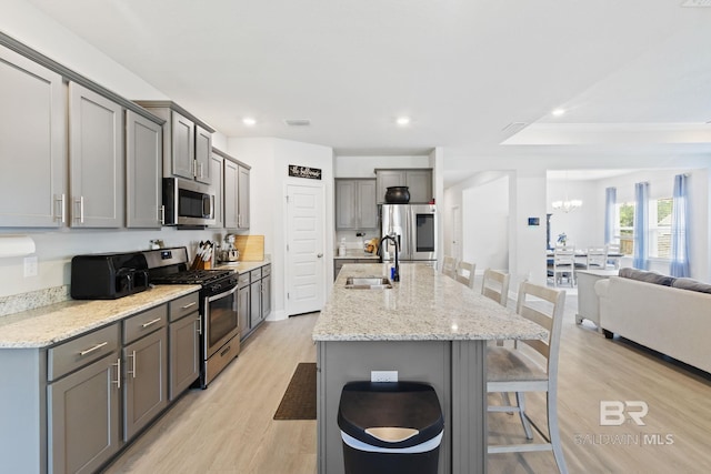 kitchen featuring gray cabinets, light stone counters, light hardwood / wood-style flooring, and appliances with stainless steel finishes