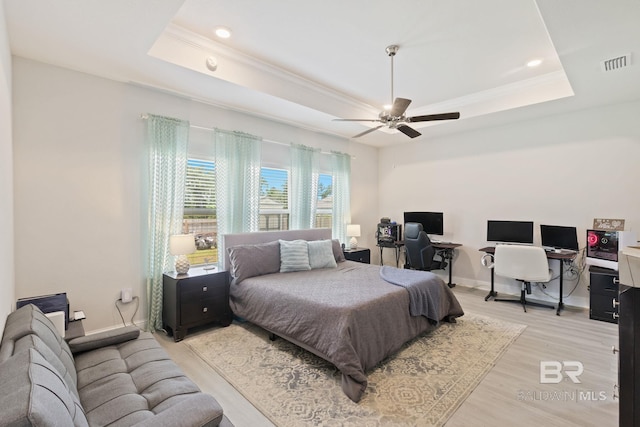 bedroom featuring a raised ceiling, light wood-type flooring, and ceiling fan