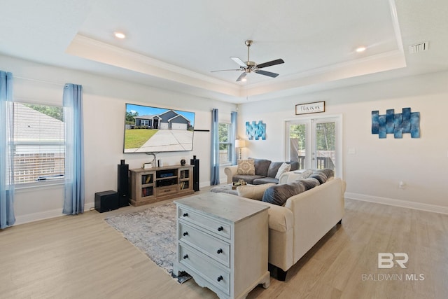 living room featuring light hardwood / wood-style floors, french doors, ceiling fan, and a raised ceiling