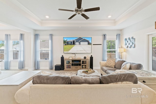 living room featuring a raised ceiling, crown molding, and ceiling fan