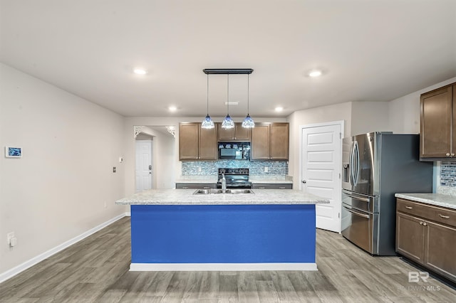 kitchen with light wood-type flooring, a sink, backsplash, appliances with stainless steel finishes, and light countertops