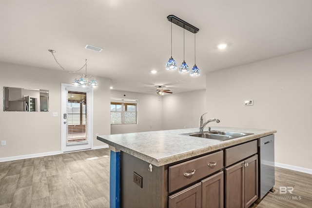 kitchen featuring visible vents, a sink, pendant lighting, light wood-style flooring, and stainless steel dishwasher